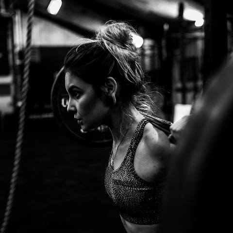 Девушка делает приседание со штангой